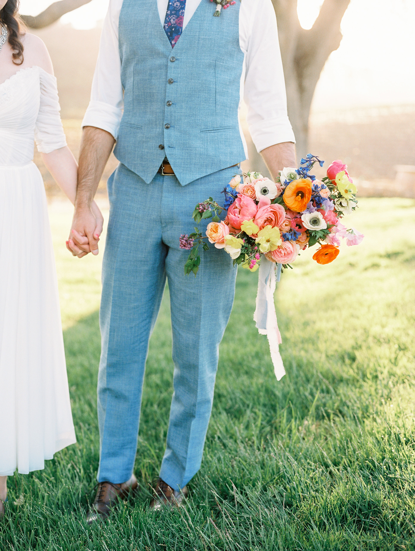 Groom holds bridal bouquet with vibrant colors at Elopement Photography in Wine Country at Hammersky Vineyards
