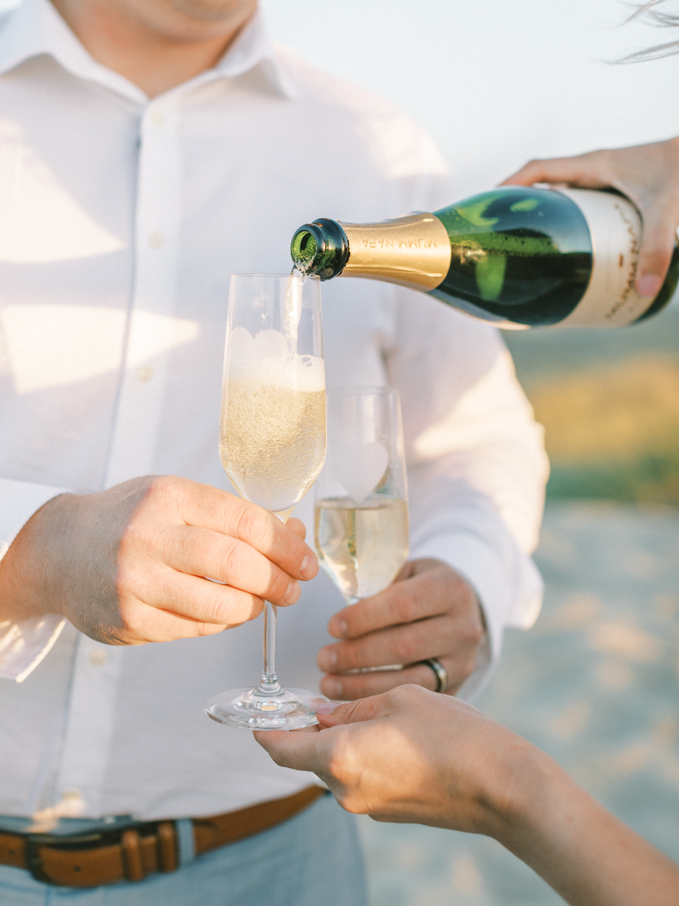 pouring champagne on the beach during ethereal engagement photography at Morro Rock