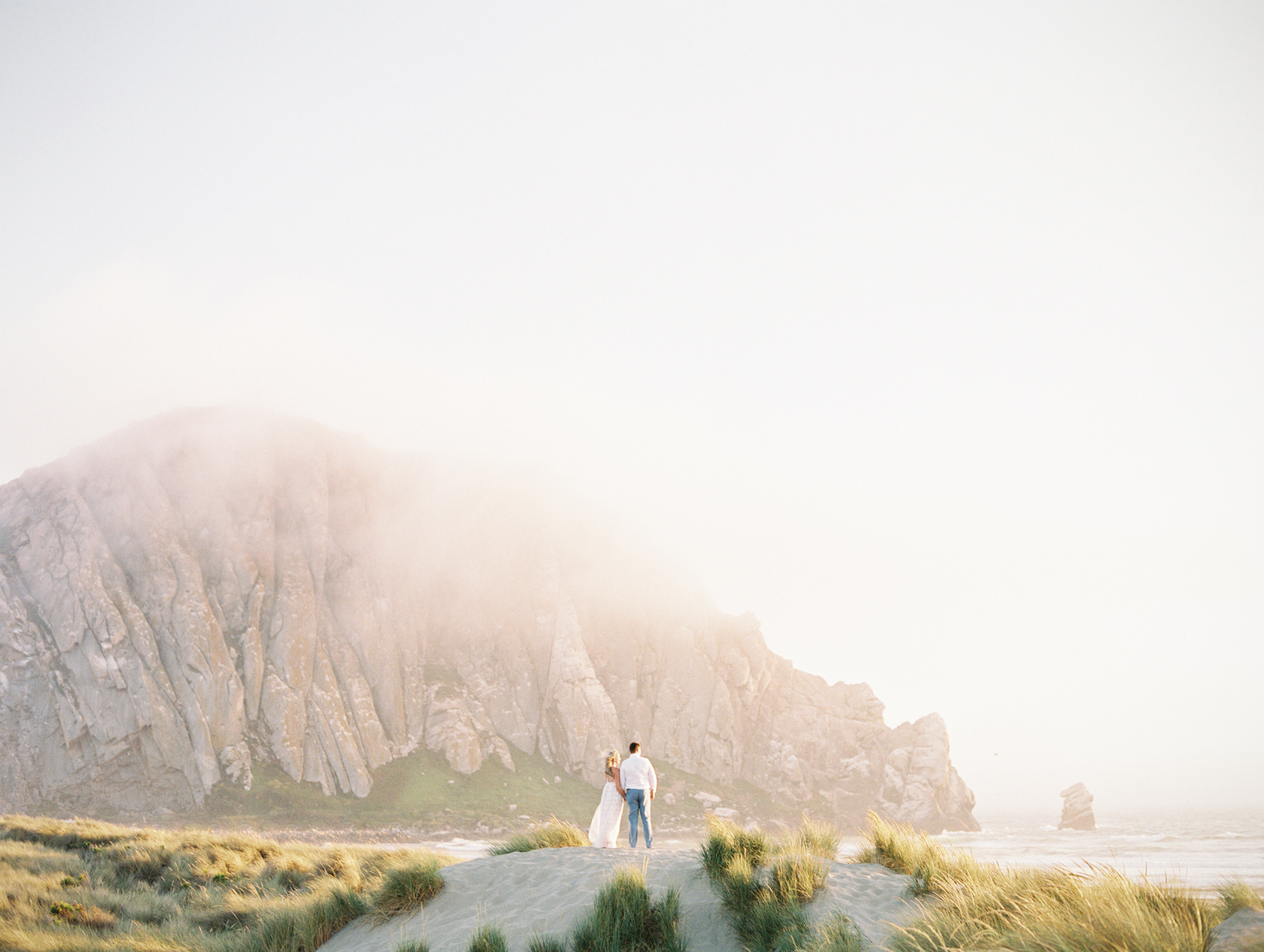 engaged couple looking out to the ocean their ethereal engagement photography at Morro Rock