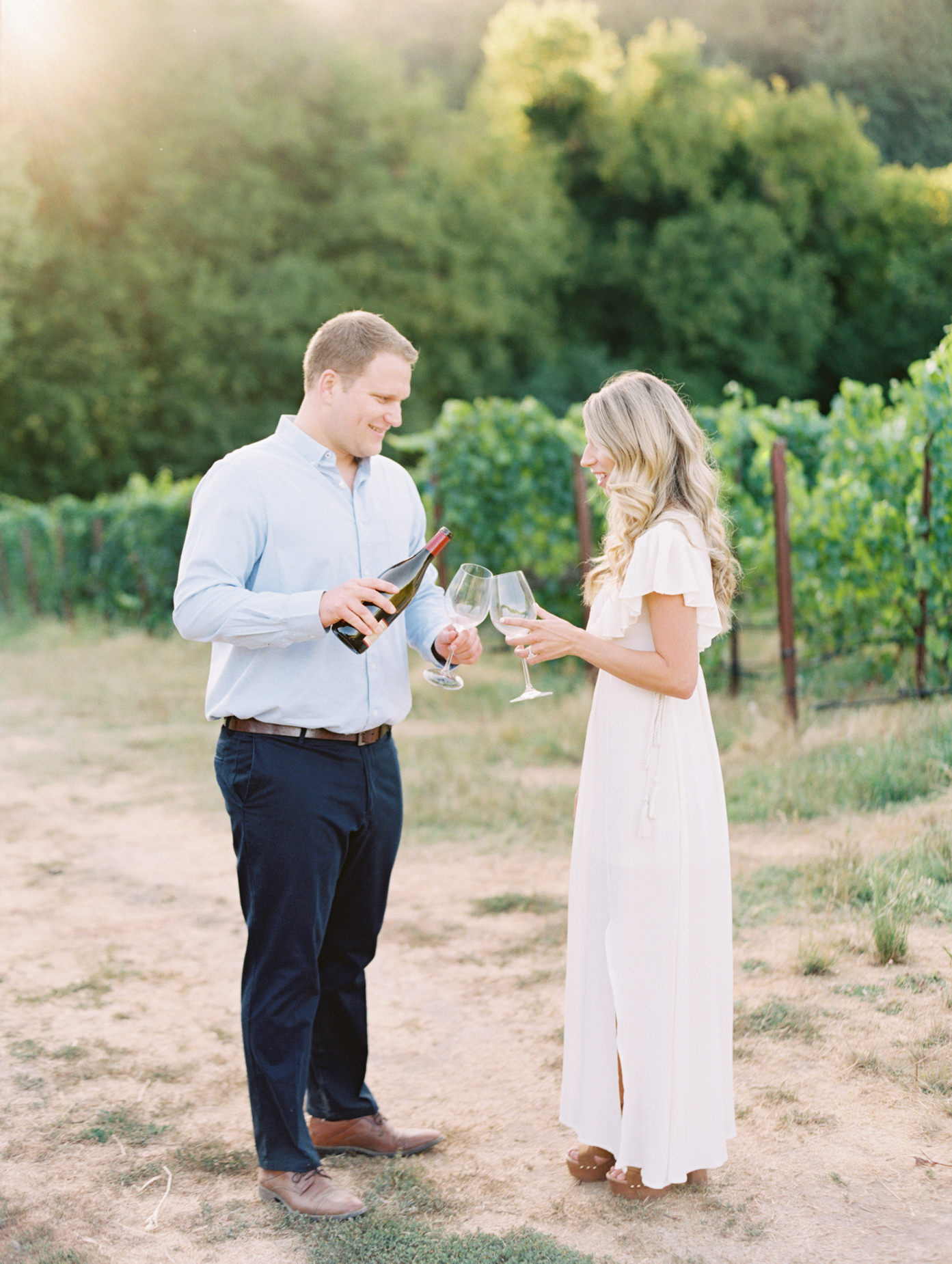 Engaged couple pouring wine at vineyard engagement at Williams Selyem Wines